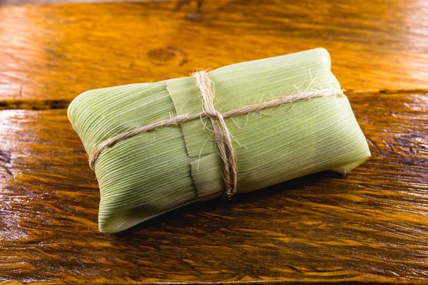 pamonha-Brazilian typical of rural towns. Sweet corn with cheese served in straw. Concept of rural and regional Brazilian food.