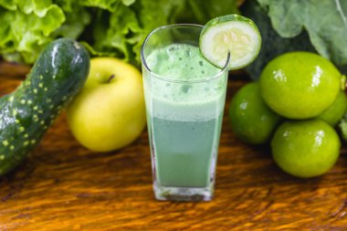 Koyu ahşap arka plan üzerinde yeşil yüzlü. Sağlıklı smoothie bitkisel kokteyl. Yeşil meyve ve sebzeler. Sağlıklı gıda ve diyet konsepti.