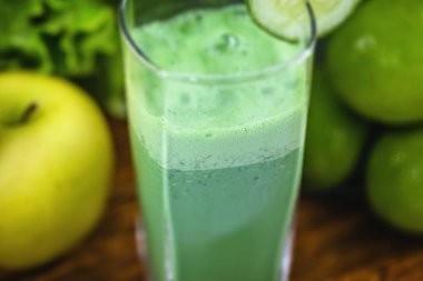 Koyu ahşap arka plan üzerinde yeşil yüzlü. Sağlıklı smoothie bitkisel kokteyl. Yeşil meyve ve sebzeler. Sağlıklı gıda ve diyet konsepti.