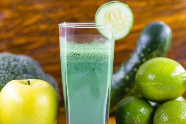 Koyu ahşap arka plan üzerinde yeşil yüzlü. Sağlıklı smoothie bitkisel kokteyl. Yeşil meyve ve sebzeler. Sağlıklı gıda ve diyet konsepti.