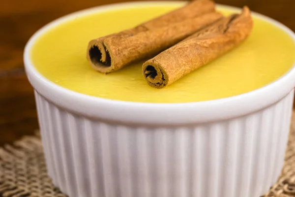 Typical Brazilian dessert, sweet of mingua, called in Brazil of curau. Typical sweet of June party. Brazilian sweet corn, corn mousse on a wooden background with copy space.