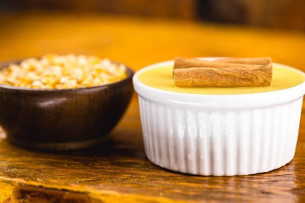 Brazilian sweet cream-like dessert cured corn mousse with cinnamon on a rustic wooden background. Typical Brazilian cuisine sweet in traditional parties, on a wooden background with copy space.
