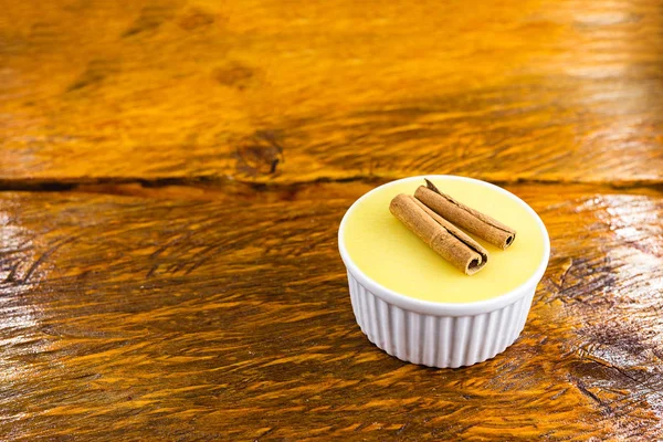 Typical Brazilian dessert, sweet of mingua, called in Brazil of curau. Typical sweet of June party. Brazilian sweet corn, corn mousse on a wooden background with copy space.