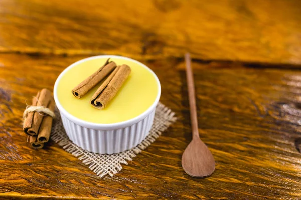 Typical Brazilian dessert, sweet of mingua, called in Brazil of curau. Typical sweet of June party. Brazilian sweet corn, corn mousse on a wooden background with copy space.