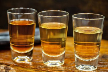 Brezilya altın ve beyaz cachaca rustik ahşap arka plan izole iki shot gözlük. Brezilya'dan tipik içecek.