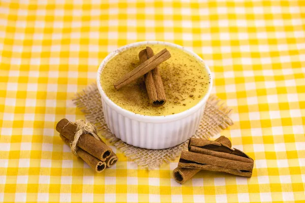 Dessert of curau. Brazilian sweet corn, corn mousse with cinnamon on a wooden background. Typical Brazilian dessert, sweet of June party. Dessert, canjica or Jimbel