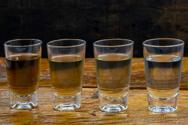 Varios vasos de cachaca brasileña aislados sobre fondo rústico de madera, variaciones y tipos de cachaca brasileña, bebida típica de Brasil . — Foto de Stock