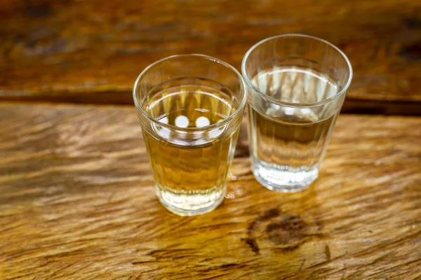 Diversi bicchieri di cachaca brasiliana isolati su fondo rustico in legno, variazioni e tipi di cachaca brasiliana, bevanda tipica del Brasile . — Foto Stock