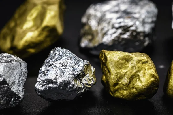 Siyah zemin üzerine altın ve gümüş külçeler. Değerli taşlar, lüks konsept ve mineral drenajı. Endüstriyel faaliyet, hazine ve servet.