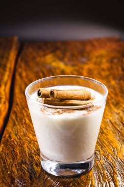 Tahta arka planda tarçınlı lezzetli sütlaç..