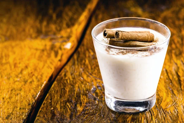 Tahta arka planda tarçınlı lezzetli sütlaç..