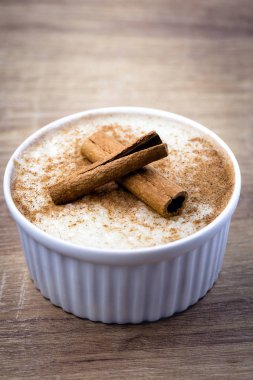 Tarçınlı pirinç lapası, açık ahşap arka planda bir kasede. Yukarıdan izlenen yiyecekler