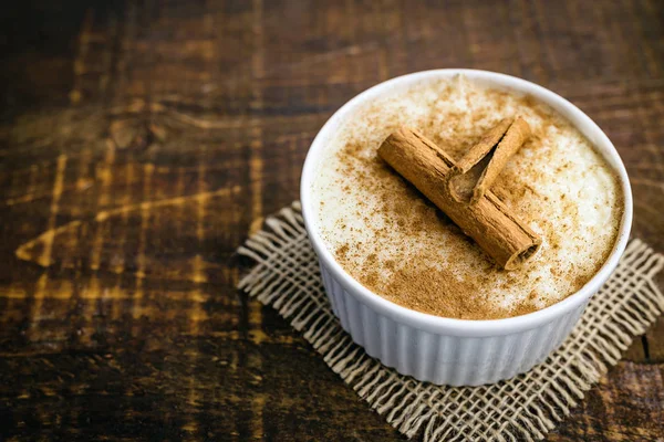 Pudim de arroz cremoso polvilhado com canela, típica sobremesa brasileira. Sobremesa saborosa no fundo de madeira rústica . — Fotografia de Stock