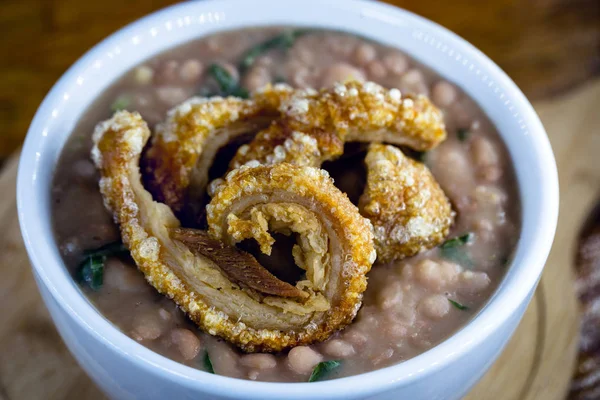 Purê de feijão com salsicha e casca de porco chamado Tutu de Feijao no Brasil. Feijão brasileiro com grande pedaço de carne de porco. Comida típica brasileira. Conceito de turismo gastronómico . — Fotografia de Stock