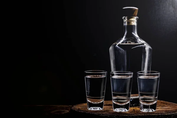 Aguardiente veya aguardente Geleneksel İspanyol ve Brezilya alkollü içecek, güçlü içecek, üzüm brendi, rom, cin, gümüş tekila, pinga, Brezilya cachaca, Rus votka, eski bir rustik ahşap masa üzerinde gözlük, metin için yer. Geleneksel içki — Stok fotoğraf