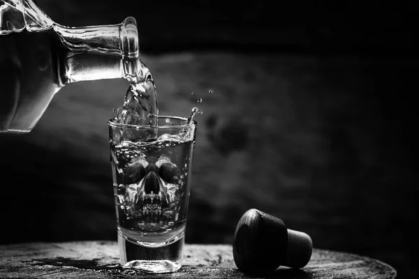 Drink bottle and glass with alcohol content. Image of translucent skull in glass. Alcoholism, addiction or poison concept. — Stock Photo, Image