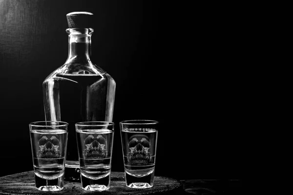 İçecek şişe ve cam alkol içeriği ile. Camda yarı saydam kafatası görüntüsü. Alkolizm, bağımlılık veya zehir kavramı. — Stok fotoğraf