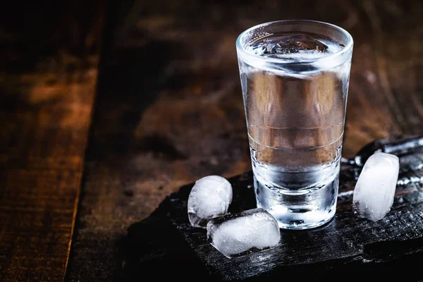 Cold cocktail with tonic, vodka and ice on the wooden background. World Vodka or Brandy Day — Stock Photo, Image