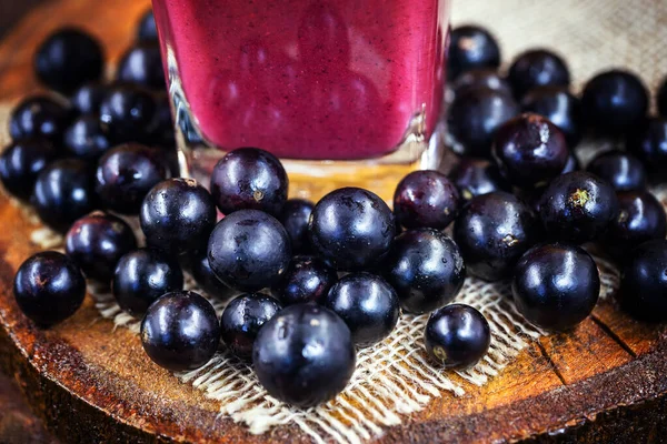 Organic Brazilian home made juice made with the fruit known as jabuticaba or jaboticaba. Juice of purple color on rustic wooden background. Fruit of the October season.