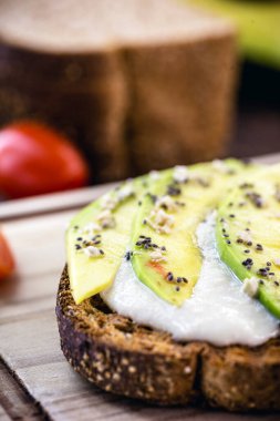 Lezzetli avokado gevrek tostun üzerinde, tahıl ve baharatla dilimlenmiş. Sağlıklı kahvaltı, diyet konsepti.