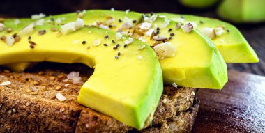 Lezzetli avokado gevrek tostun üzerinde, tahıl ve baharatla dilimlenmiş. Sağlıklı kahvaltı, diyet konsepti