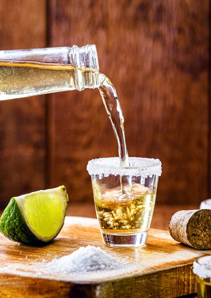 tequila bottle filling glass of drink. Typical mexican drink being served.