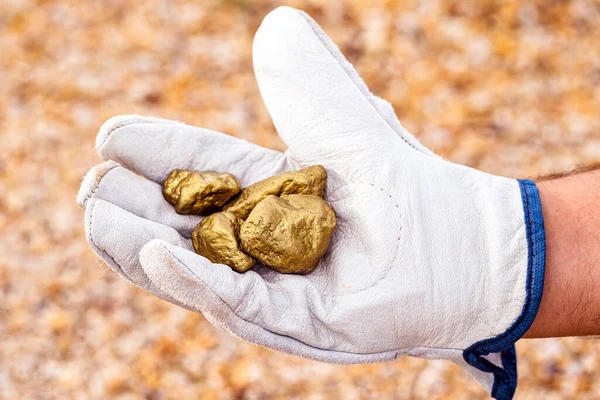 miner hand holding stones from another, gold mineral extraction, precious stone exploration concept.