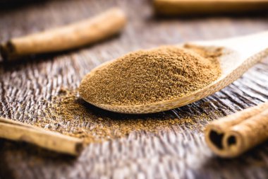 Kırsal ahşap arka planda bir kaşık tarçın. Organik mutfak malzemesi..