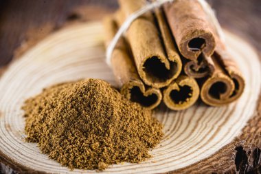 Tarçın tozu ve sade ahşap. Tedavi edici özellikleri olan Hint tarçını