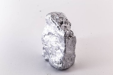 Beyaz arka planda izole edilmiş nikel metal parçasının makro çekimi. Endüstride kullanılan parlak kaba mineral krom taşının yakın plan fotoğrafı.