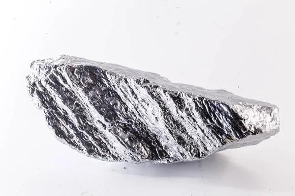 Beyaz arka planda izole edilmiş nikel metal parçasının makro çekimi. Endüstride kullanılan parlak kaba mineral krom taşının yakın plan fotoğrafı.