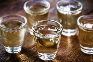 Brezilya altın cachaca bardakları, damıtılmış içecek, kırsal ahşap arka planda.