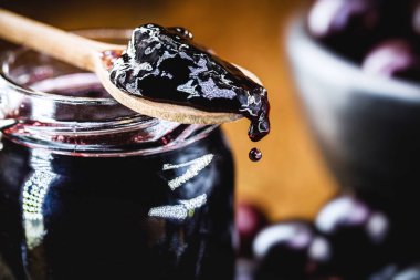 Brezilya üzümü olarak bilinen tipik bir Brezilya meyvesi olan jabuticaba (veya jaboticaba) jölesi, ahşap kaşıktan yapılan organik jöle, damlayan lezzetli şeker damlası.