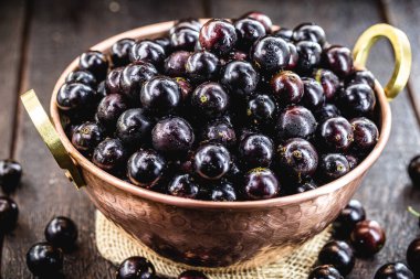 Jabuticaba. Brezilya ve Güney Amerika tropikal meyveleri, kırsal bir masada bakır bir tencerede