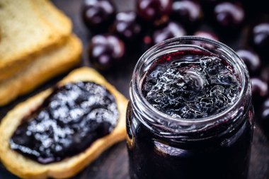 Kırsal ahşap masada üzüm reçelli tost. Jabuticaba, egzotik Brezilya meyvesi, yemek pişirmede tatlı olarak kullanılır..