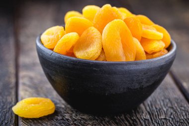 Kurutulmuş ve kurutulmuş kayısı, el yapımı kil bir tencerenin içinde, kırsal ahşap arka plan ve metin için alan