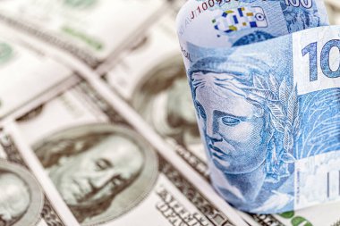 Brezilya 'dan gelen 100 reais banknotun ayrıntıları. 100 Amerikan dolarının banknotları arasında sıkıştı. Ekonomik kriz ve Amerikan para biriminin yükselişi