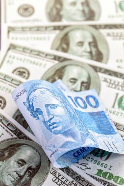 Brezilya 'dan gelen 100 reais banknotun ayrıntıları. 100 Amerikan dolarının banknotları arasında sıkıştı. Ekonomik kriz ve Amerikan para biriminin yükselişi