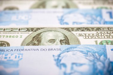Brezilya 'dan gelen 100 reais banknotun ayrıntıları. 100 Amerikan dolarının banknotları arasında sıkıştı. Ekonomik kriz ve Amerikan para biriminin yükselişi