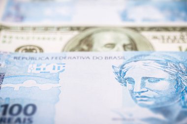 Brezilya 'dan gelen 100 reais banknotun ayrıntıları. 100 Amerikan dolarının banknotları arasında sıkıştı. Ekonomik kriz ve Amerikan para biriminin yükselişi