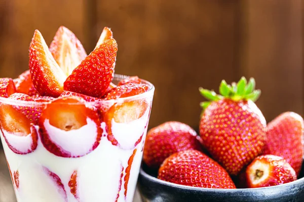 jar of fresh decorated strawberry, with condensed milk, and fresh fruit in the background