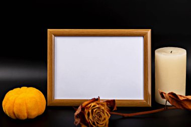 Cadılar Bayramı. Modelleme. Fotokopi alanı olan boş ahşap çerçeve, sonbahar yaprakları, küçük balkabağı ve mumlarla sanatsal olarak düzenlenir. Mevsimsel dekorasyon için sıcak ve davetkar Cadılar Bayramı atmosferi yaratır.