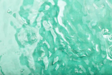 Turkuaz su arka planı. Temiz turkuaz su yüzeyi yumuşak dalgalar ve kabarcıklar sergiler ve sakin bir ortam yaratır. Işık, suyun rahatlatıcı görsel deneyimini güzel yansıtır.