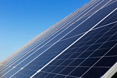 Güneş panelleri. Güneş panelleri, yenilenebilir enerji çözümlerinin ve modern yaşam için sürdürülebilir teknolojinin önemini vurgulayarak açık mavi gökyüzü altında verimli bir şekilde güneş ışığını yakalar.