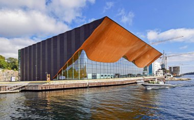 Kristiansand, Norveç - 19 Temmuz 2017: Kristiansand, Norveç'te Kilden gösteri merkezi, tiyatro ve konser salonu dış görünümü. Bir tekne yolcu ile binanın önünde kanala geçer.