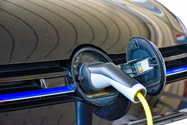 Bir elektrikli araç şarj istasyonu ücret uygulanır. Şarj fişi marka logosu gizli yuvaya takıldığından.