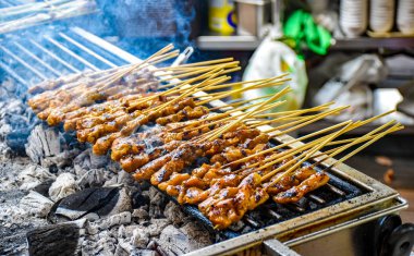 Bir kömür ızgara Satay şiş tavuk eti ile hazırlanır. Izgara duman yükselir.