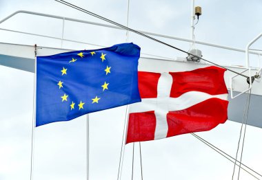 The flags of the EU and the state of Denmark side by side on a mast of a ship clipart