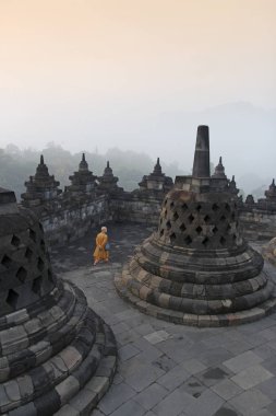 Yogyakarta, Endonezya - 22 Nisan 2018: Gizemler orman şafakta çevreleyen ile Borobudur Tapınağı dolaşan bir keşiş