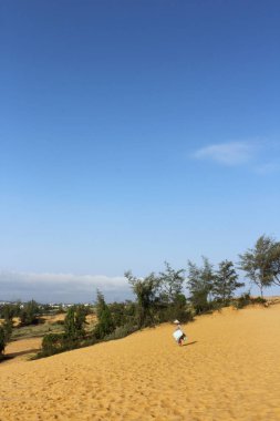 Vietnamese woman with her slide boards for rent at Red Sand Dunes, Mui Ne